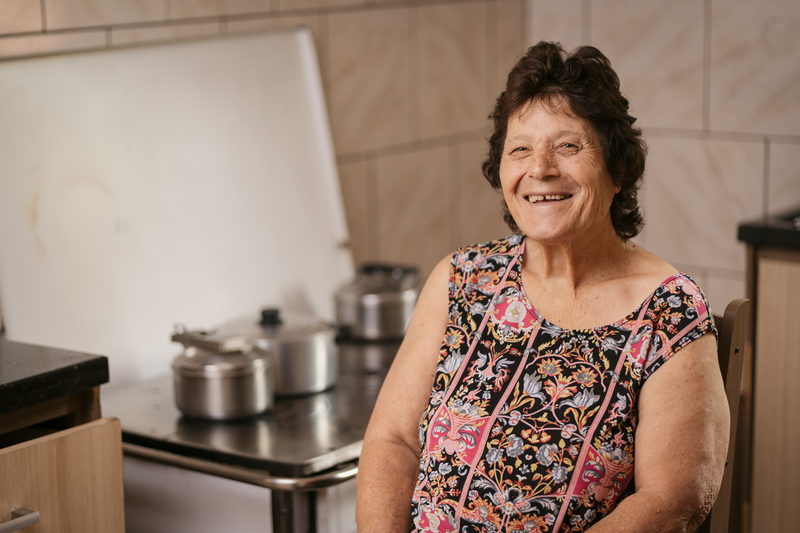 Cooperada sorrindo na cozinha de casa