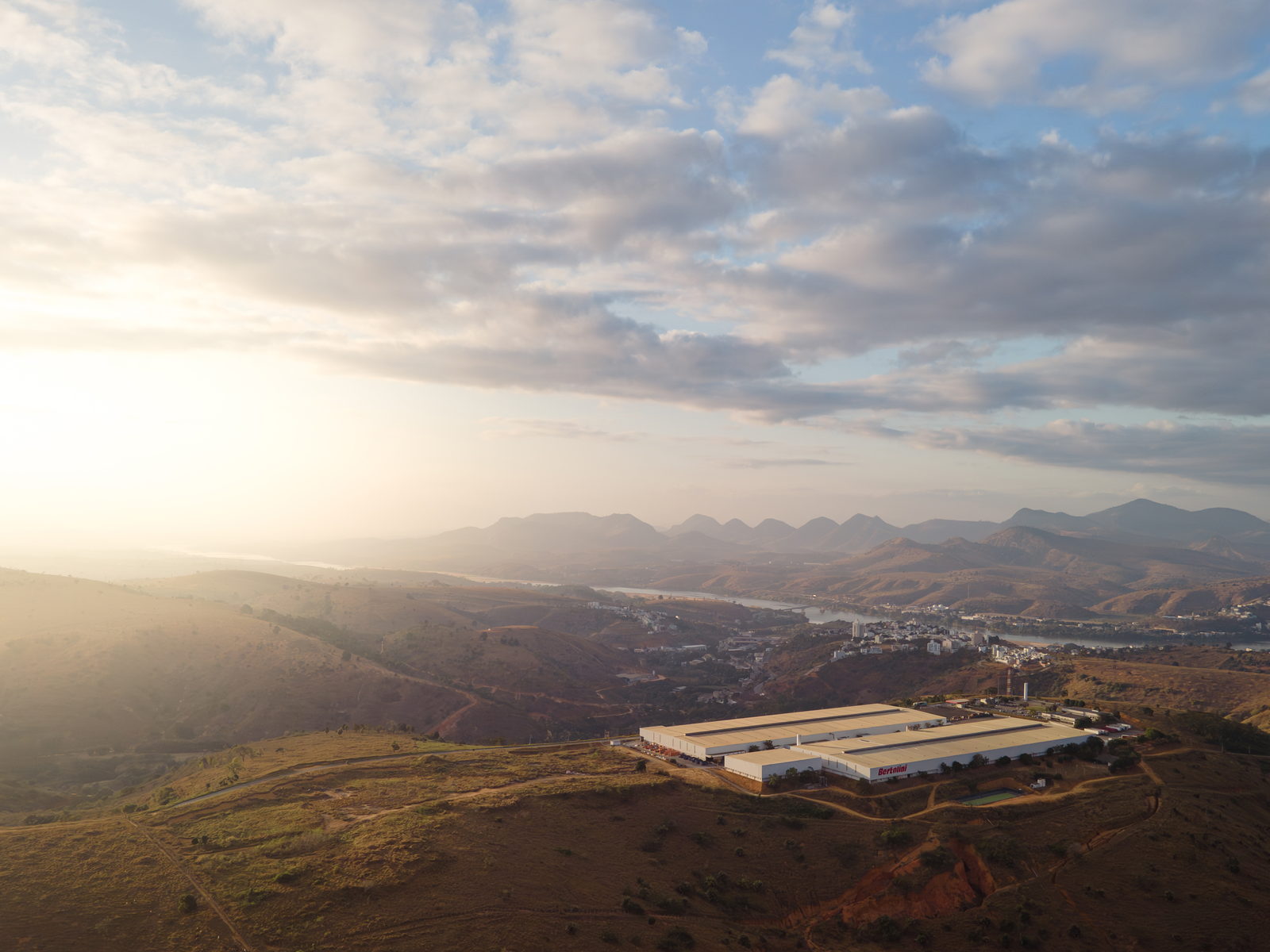 Vista aérea da unidade do Grupo Bertolini entre morros ao amanhecer