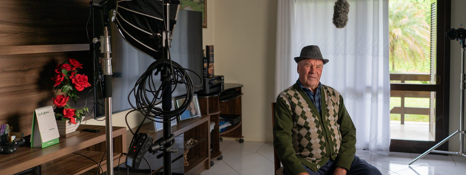 Cooperado sentado na própria sala, cercado pelo equipamento de luz e som antes da entrevista