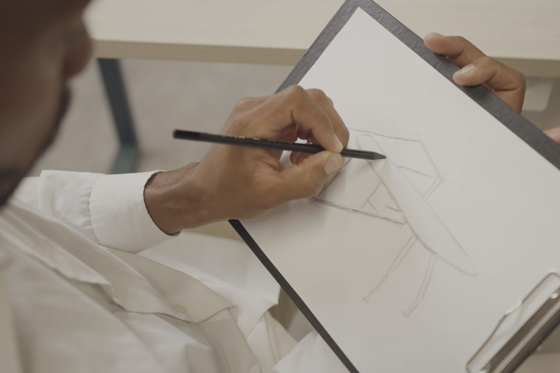 Mão desenhando a lápis sobre uma prancheta